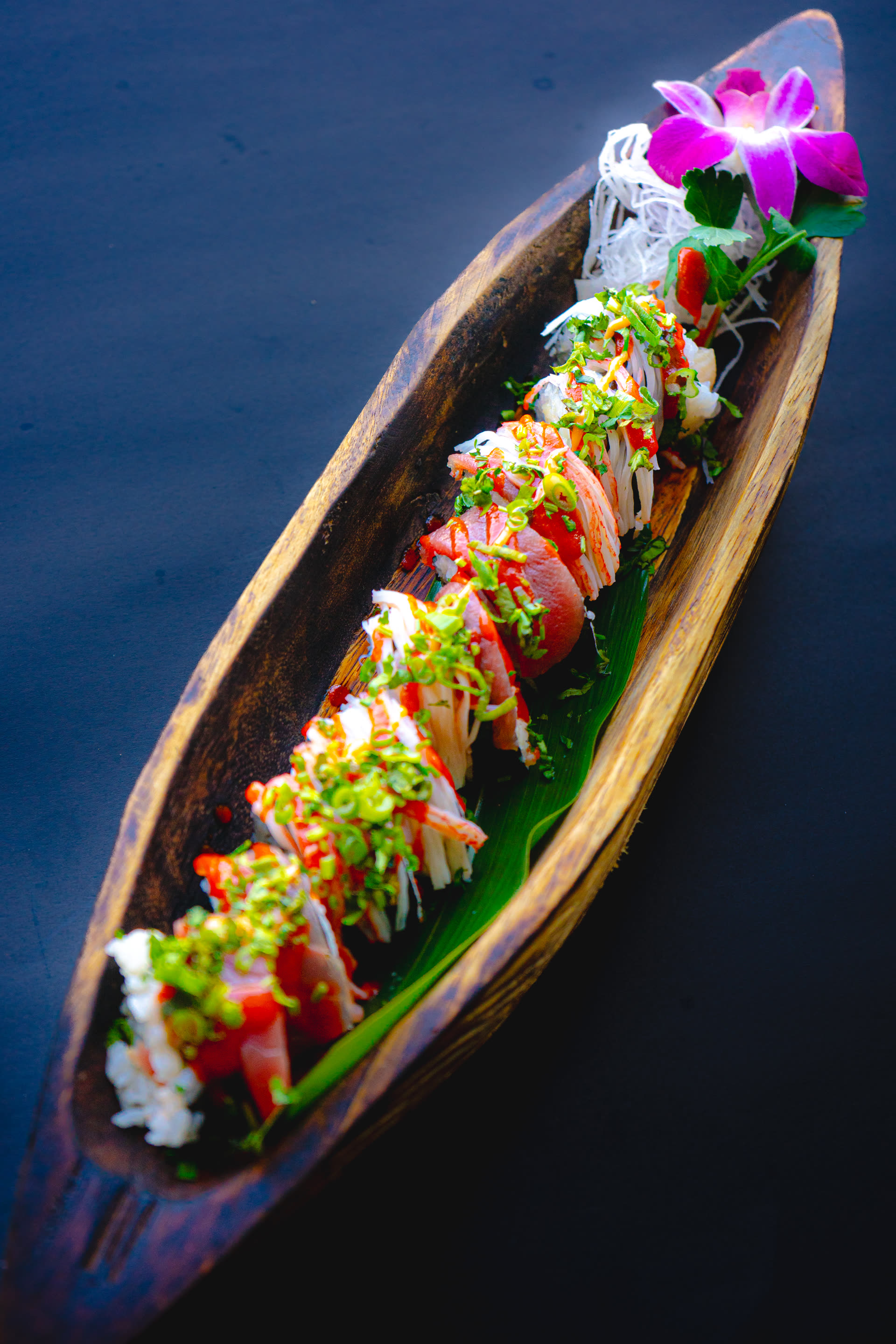 Specialty roll served in a wooden boat at Deer Park Sushi